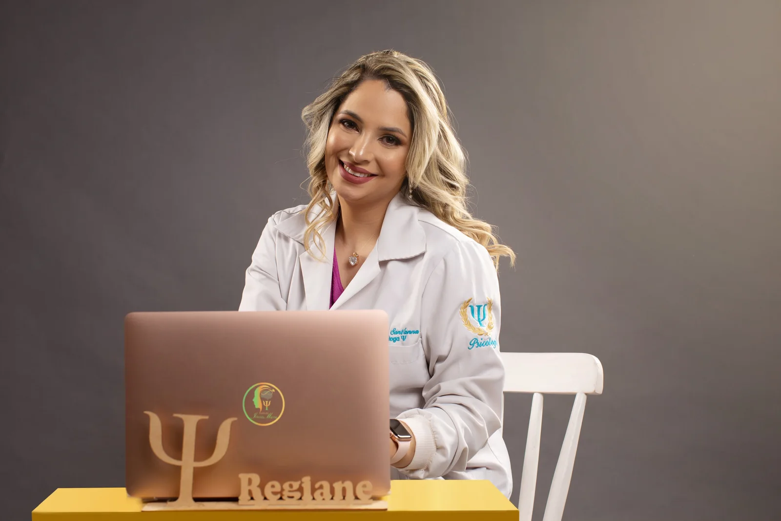 Regiane Sant’anna sorrindo, sentada com seu notebook